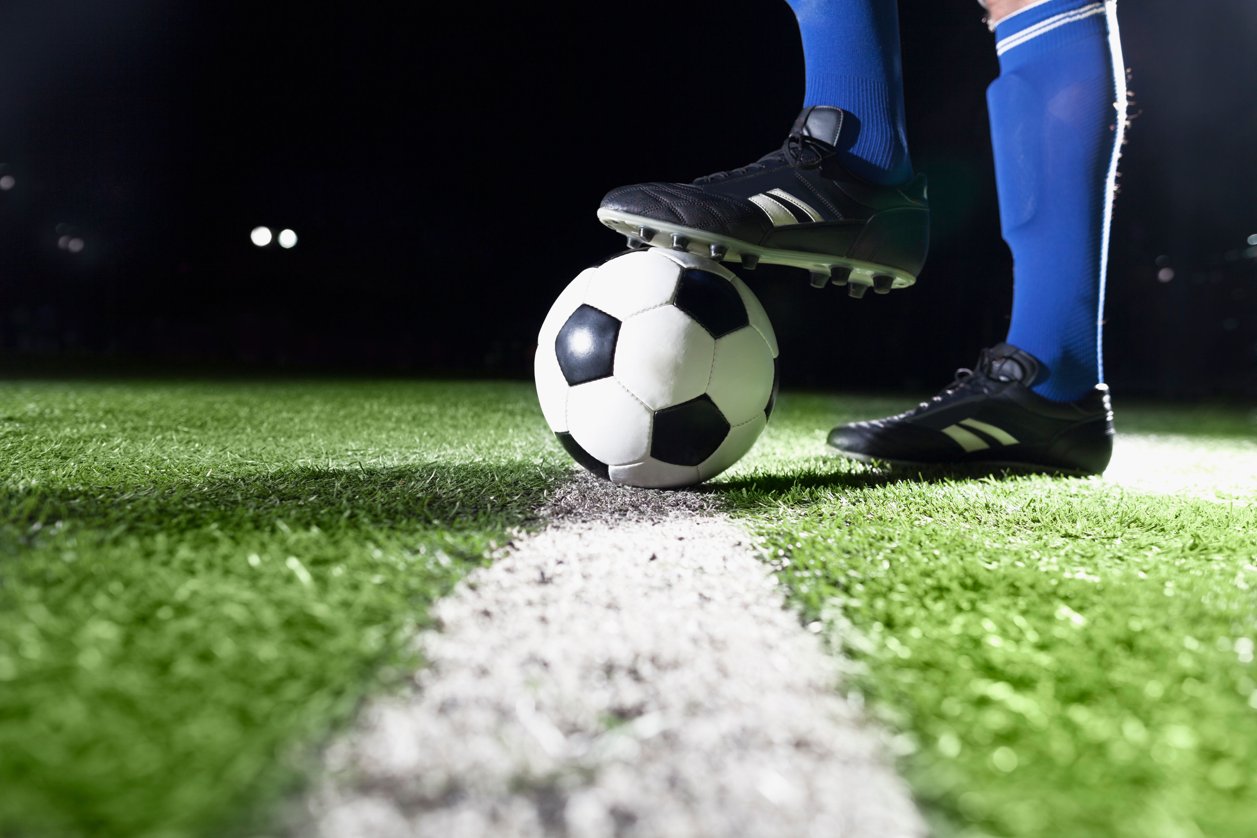 Soccer ball on pitch with player in blue socks